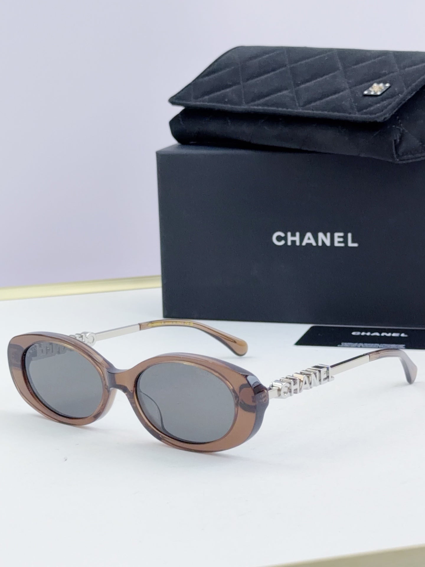 Chanel round sunglasses with light brown frames and tinted lenses, gold chain temple detail.