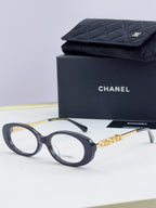 Chanel eyeglasses with dark frame, gold-tone logo temples, and clear lenses; with case.