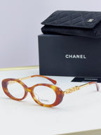 Chanel eyeglasses with tortoiseshell frame, gold-tone logo temples, and clear lenses; with case.