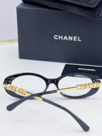Chanel eyeglasses front view: dark round frame with gold-tone chain temple logo and clear lenses.