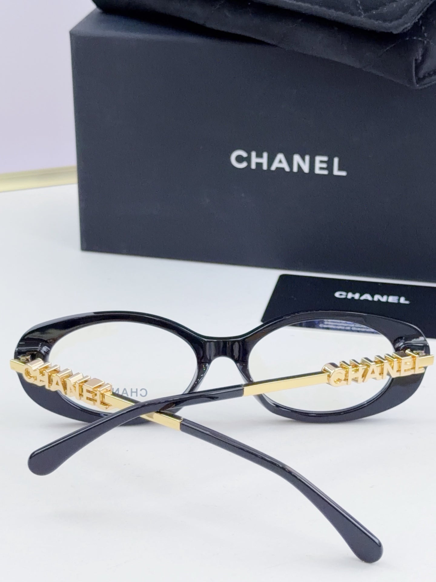 Chanel eyeglasses front view: dark round frame with gold-tone chain temple logo and clear lenses.