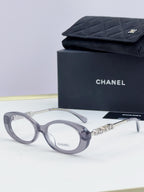 Chanel eyeglasses with gray frame, gold-tone logo temples, and clear lenses; with case.