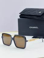 Chanel square sunglasses with dark frame, gold-tone logo arms, amber-tinted lenses