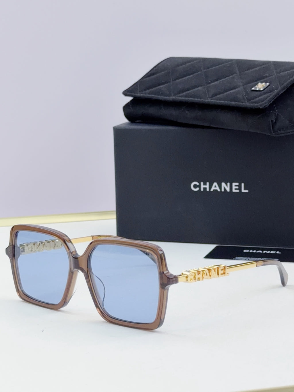 Chanel square sunglasses with tortoiseshell frame, gold-tone logo arms, pale blue lenses
