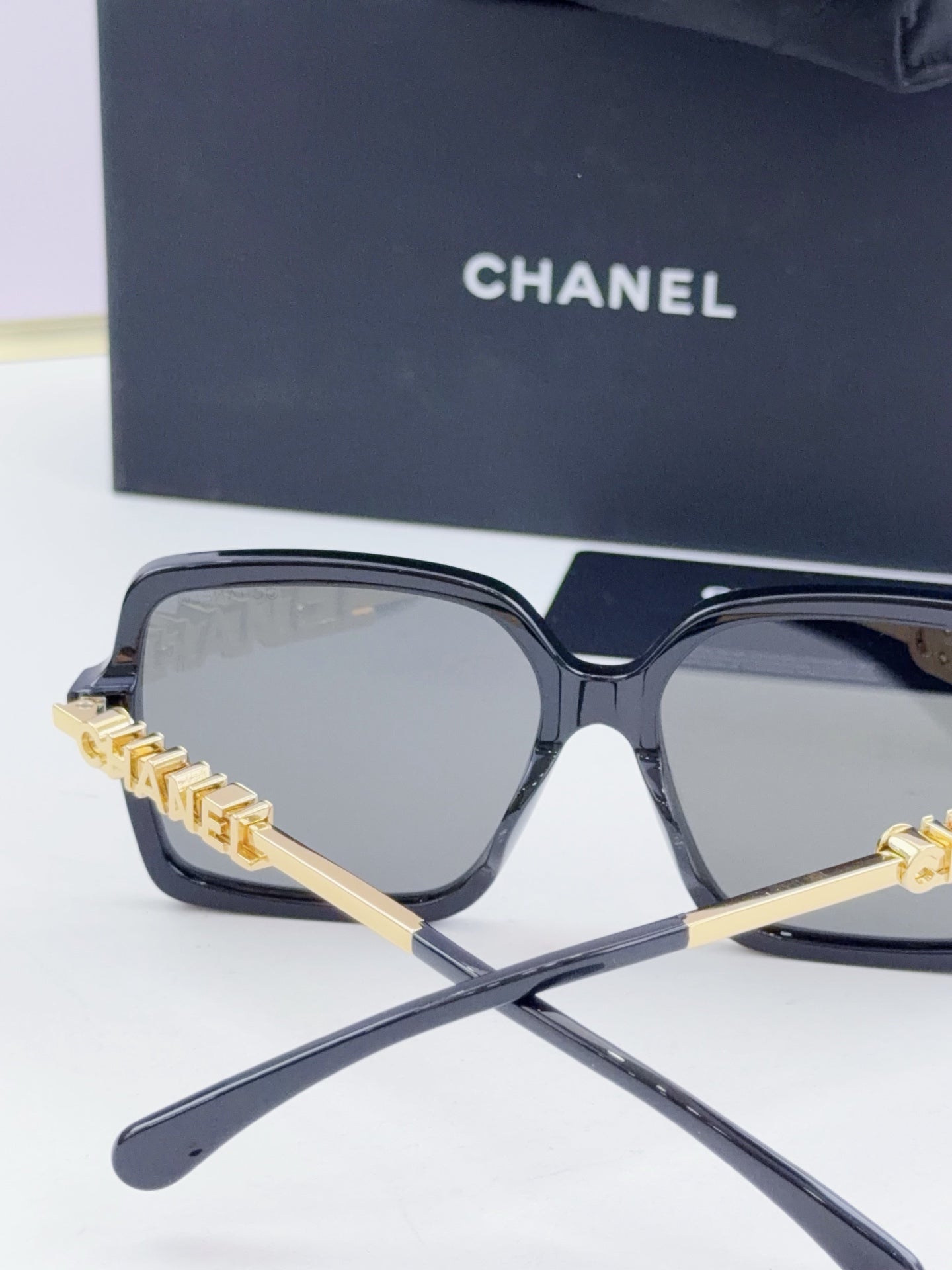 Chanel square sunglasses with dark frame, gold-tone logo arms, tinted gray-blue lenses