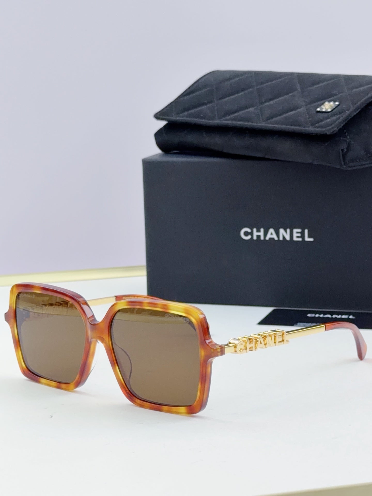 Chanel square sunglasses with tortoiseshell frame, gold-tone logo arms, amber lenses