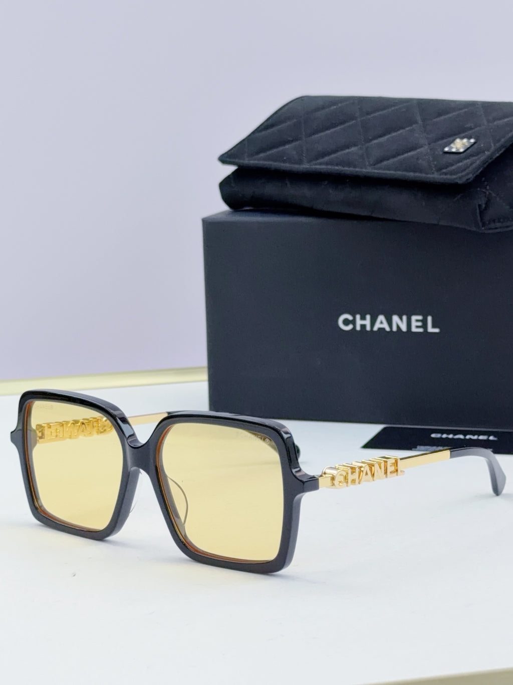 Chanel square sunglasses with dark frame, gold-tone logo arms, light yellow lenses