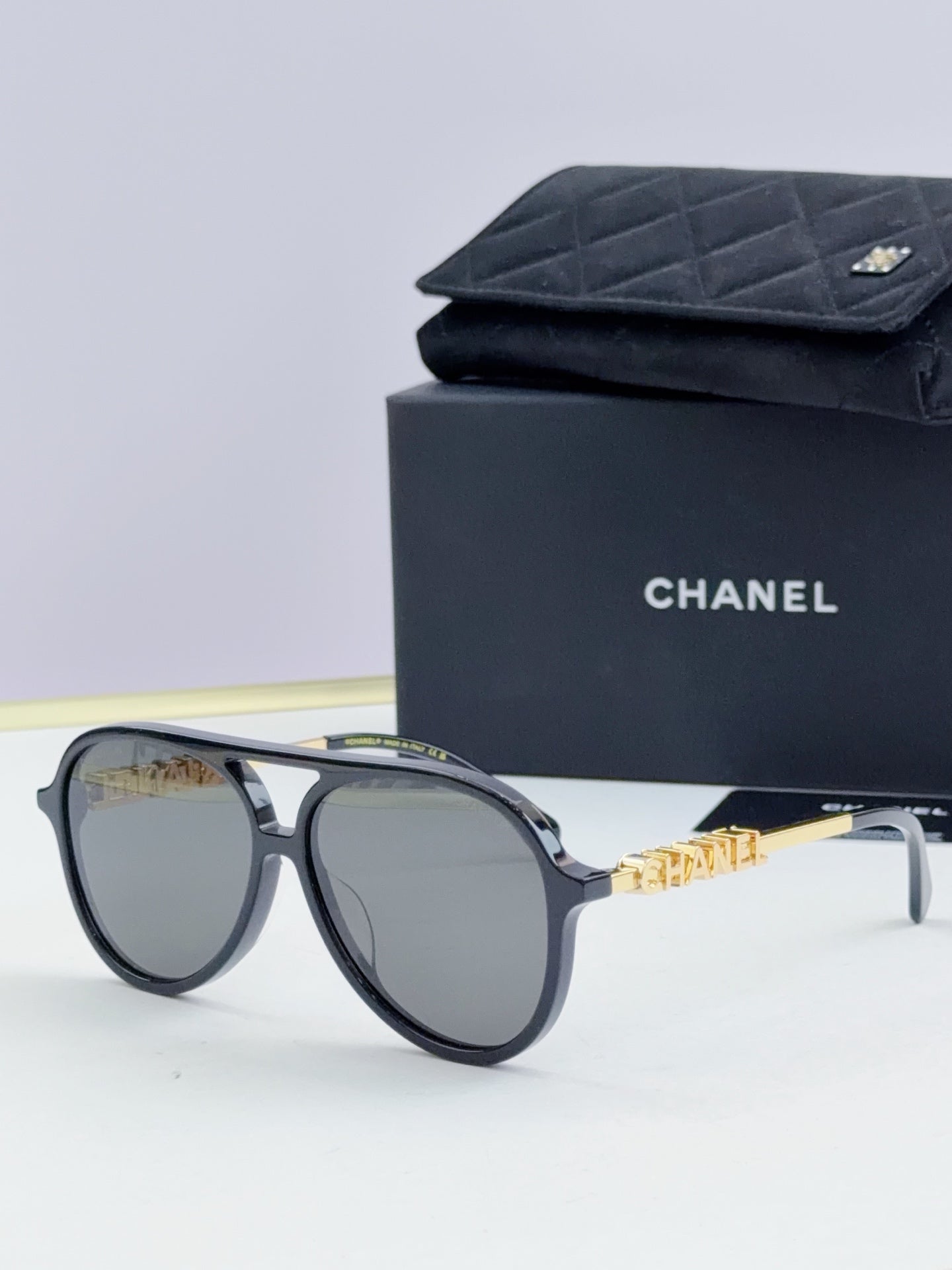 Chanel round sunglasses with dark frames, gray lenses, and gold logo temples.