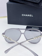 Chanel round sunglasses with silver frames and branded temples, angled view.