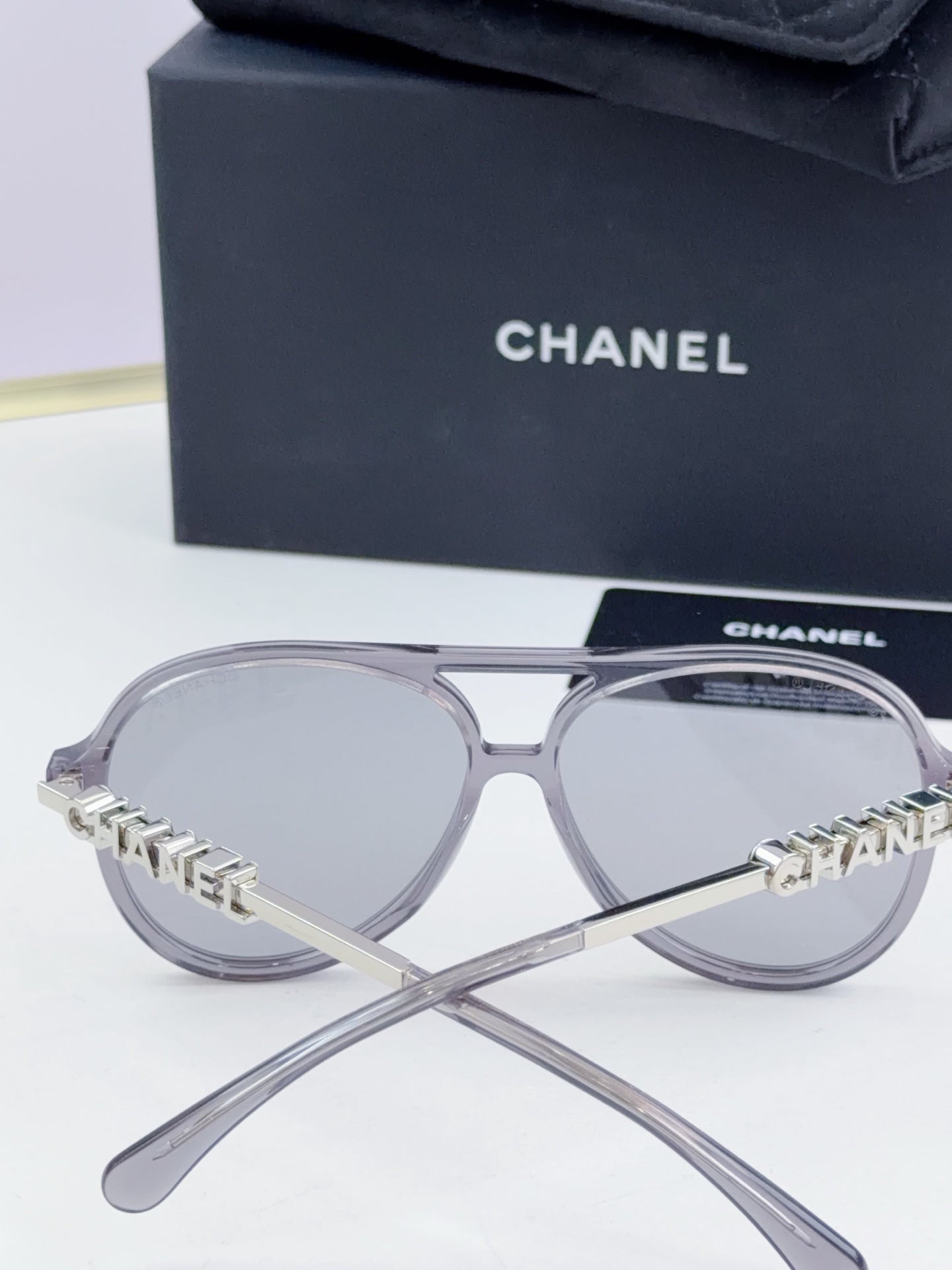 Chanel round sunglasses with silver frames and branded temples, angled view.