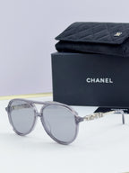 Chanel round sunglasses with silver frames and clear gray lenses, front view.