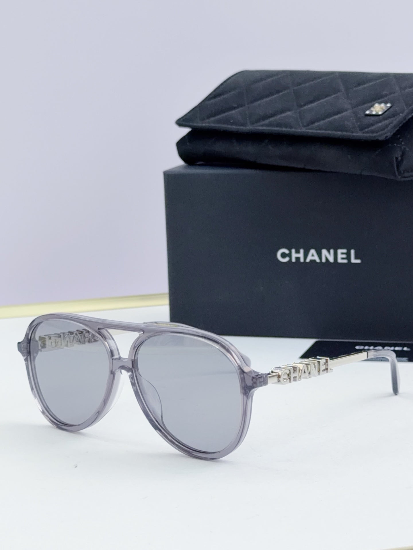 Chanel round sunglasses with silver frames and clear gray lenses, front view.
