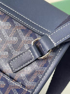 Close-up of navy flap clasp with metal ring and contrast seam stitching
