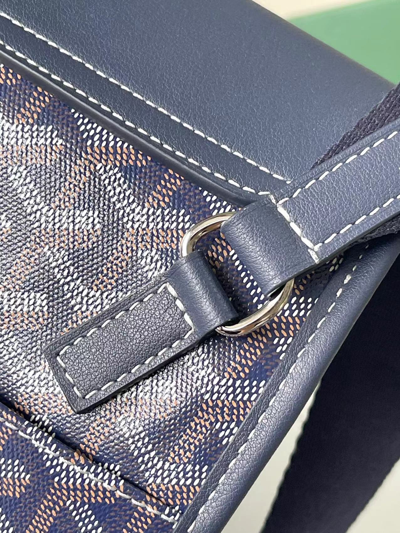 Close-up of navy flap clasp with metal ring and contrast seam stitching