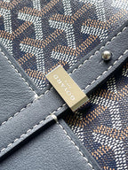 Close-up of navy monogram bag with stitched seams and attached brand tag