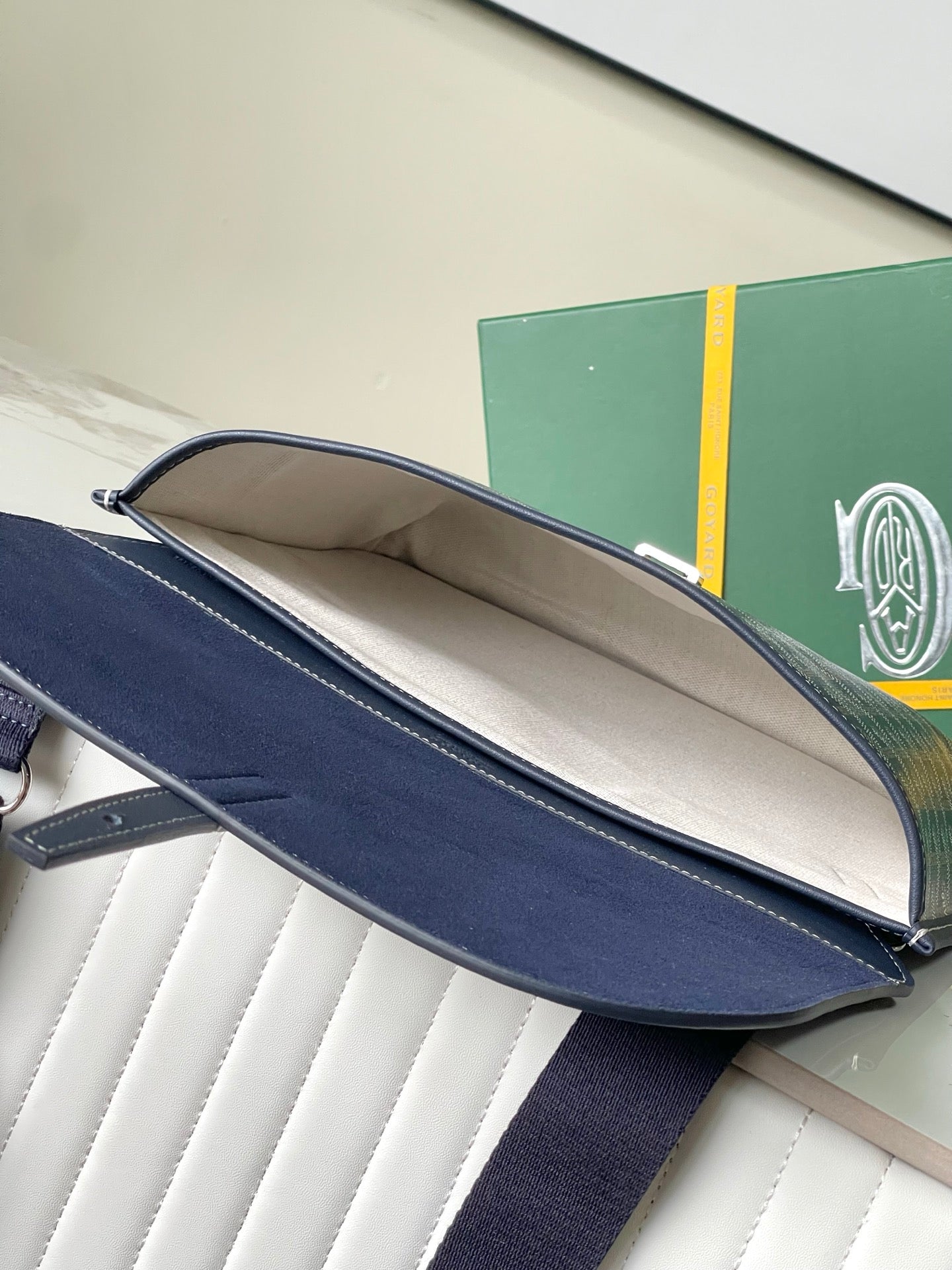 Navy crossbody bag open view with beige interior lining and shoulder strap
