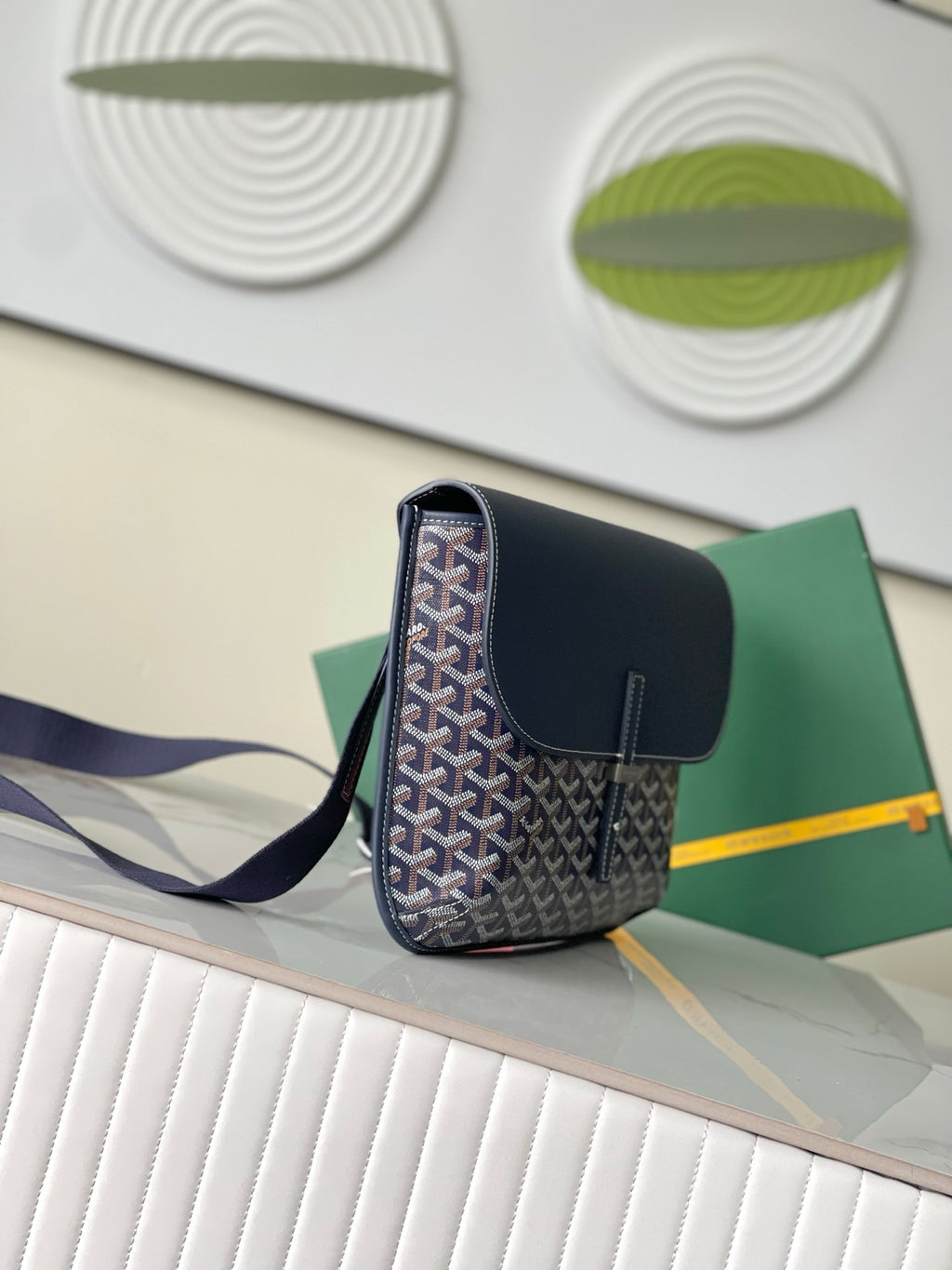 Navy crossbody bag with top flap, front monogram pattern, and shoulder strap
