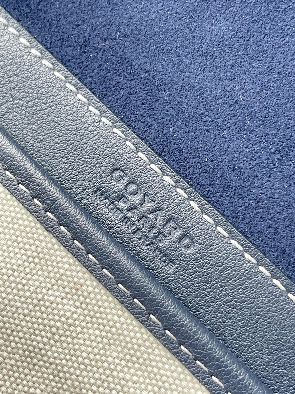 Close-up of navy leather trim with contrast stitching and embossed emblem