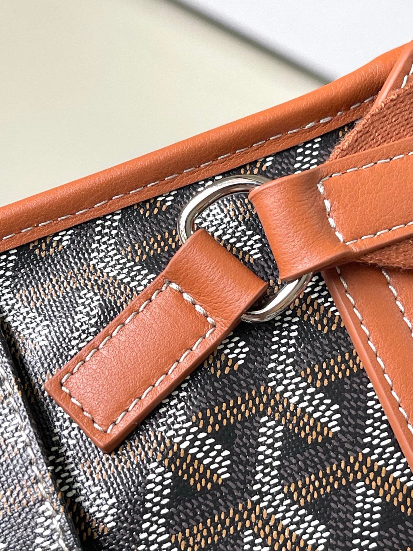 Patterned bag with tan leather handle loop and silver-ring strap attachment
