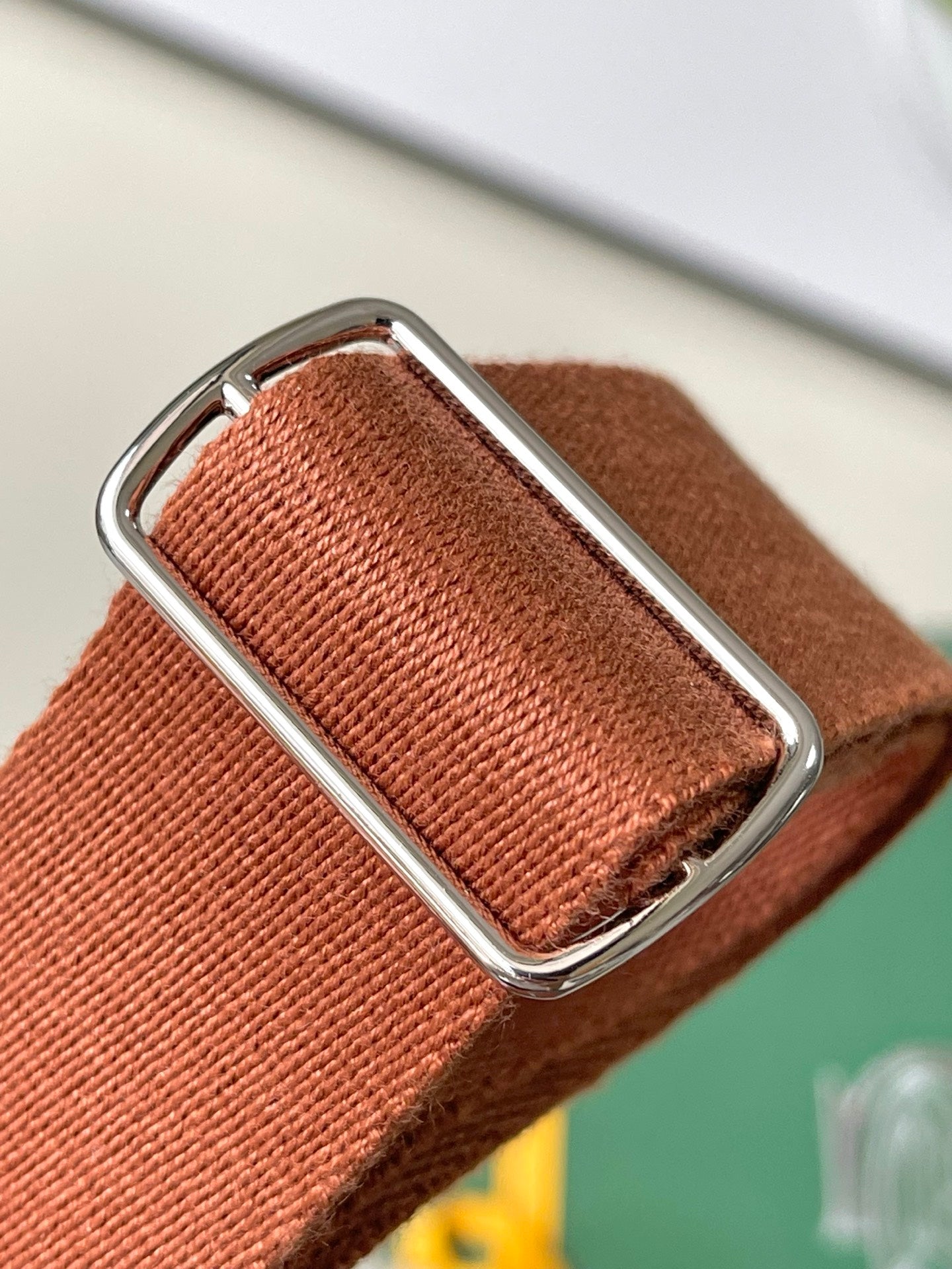 Tan webbing shoulder strap with metal buckle and stitched leather end