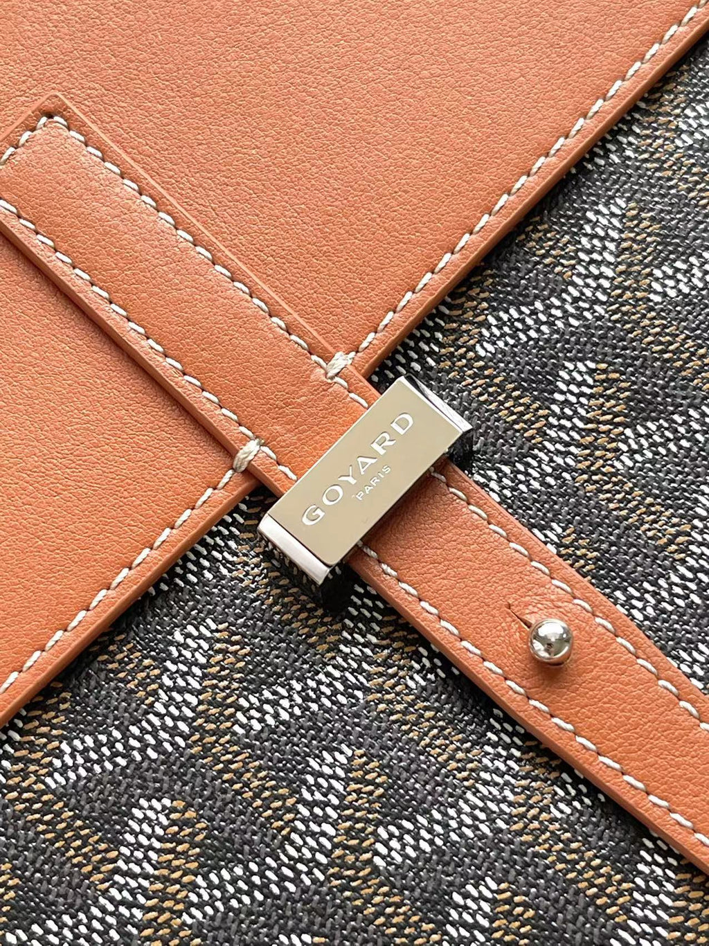 Leather strap patch with GOYARD logo on patterned bag with tan stitching
