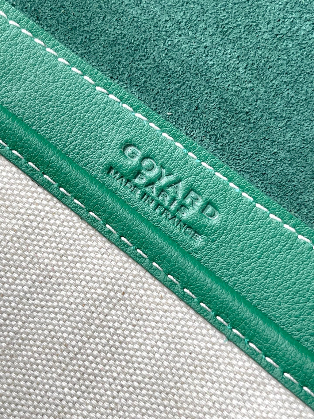 Green leather trim with white stitching and embossed Goyard text