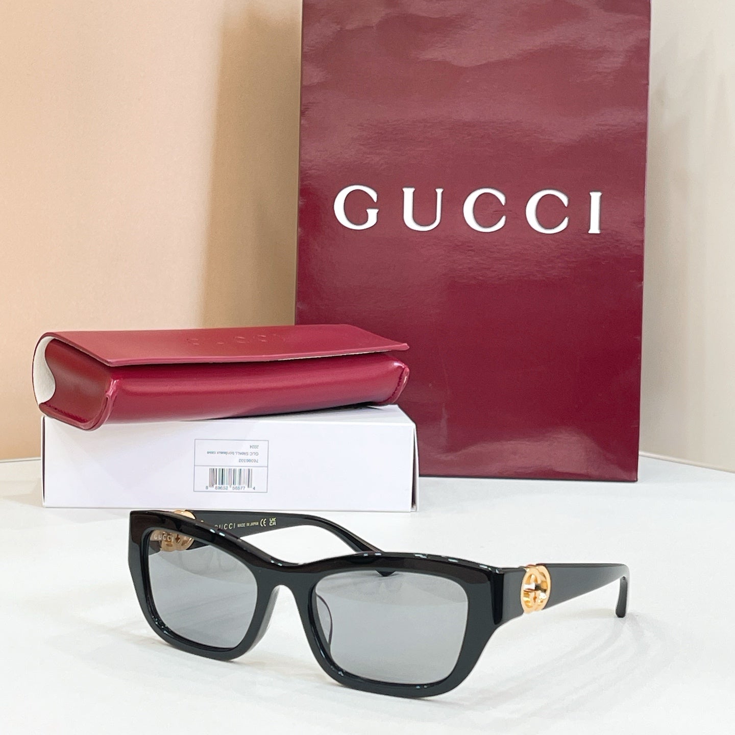 Black rectangular sunglasses with gray lenses and gold logo detail