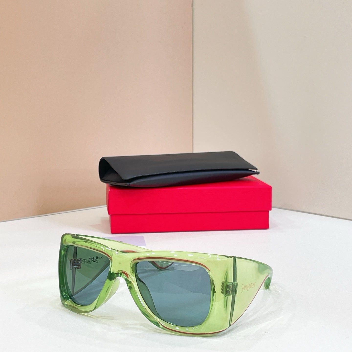 YSL sunglasses with green frames and blue-tinted lenses, with black case