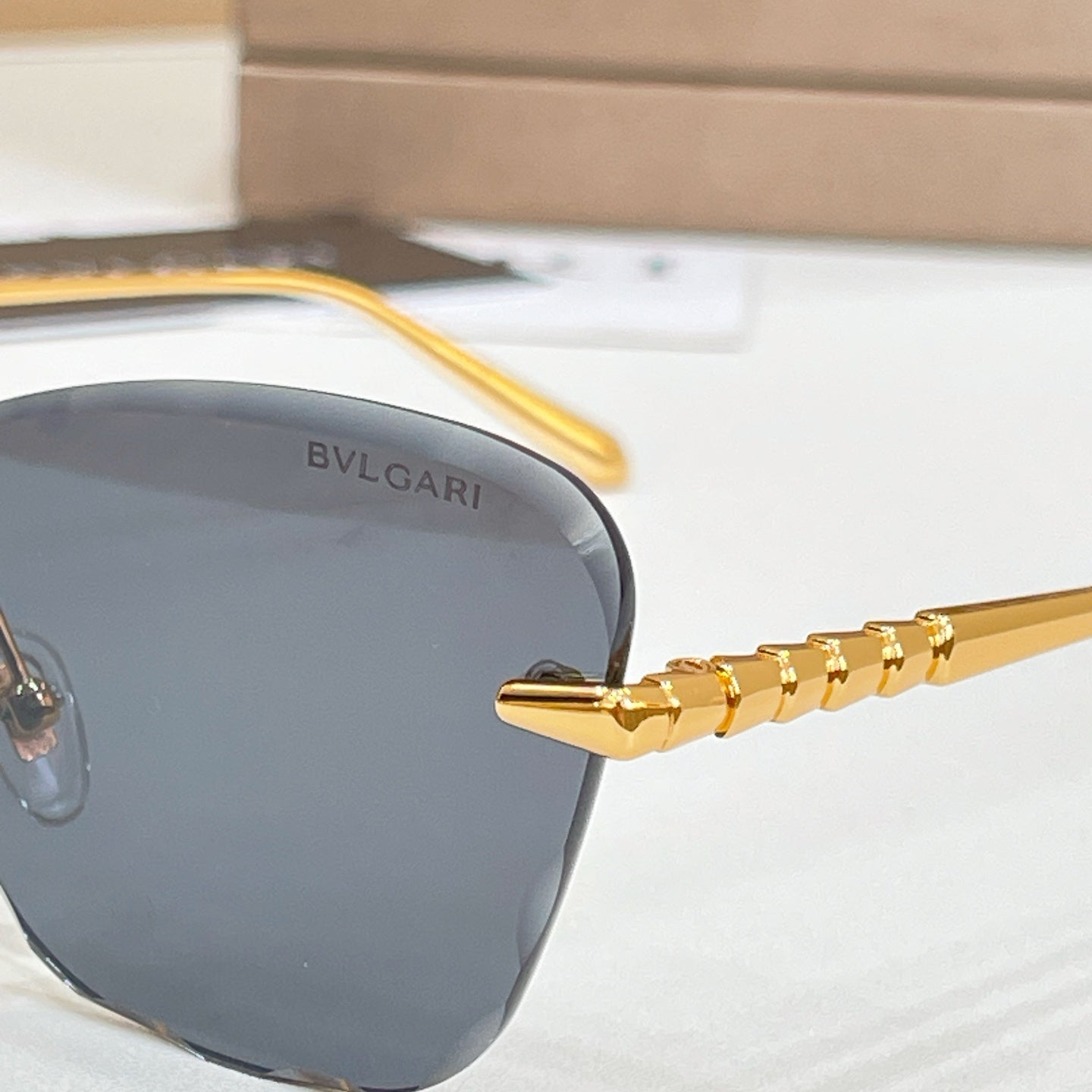 Gold-tone sunglasses with dark lenses and Bvlgari logo on frame