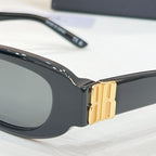 Balenciaga black sunglasses close-up with gold-tone logo hinge and dark lenses