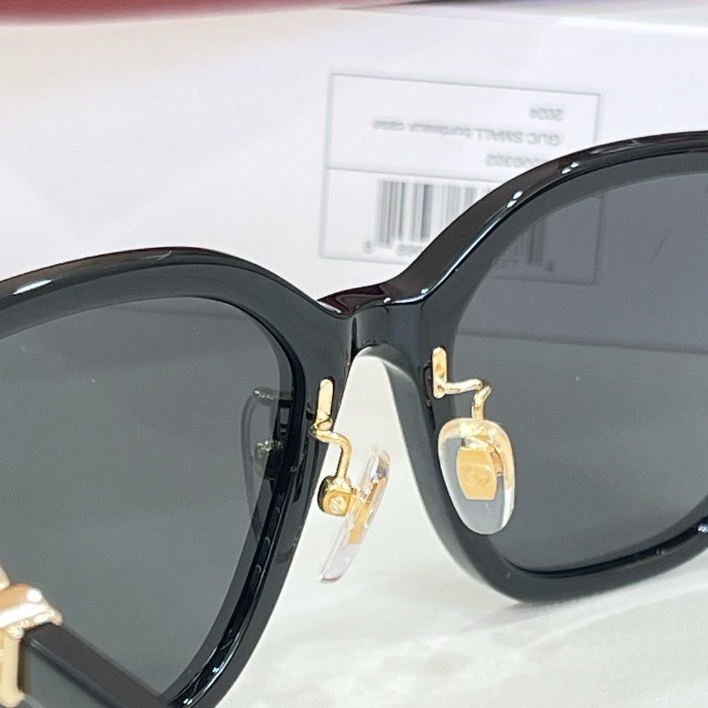 Gucci glasses close-up: black lenses and gold hinge detail on frame