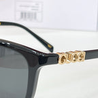 Gucci glasses close-up: black frame with gold logo detail on temple