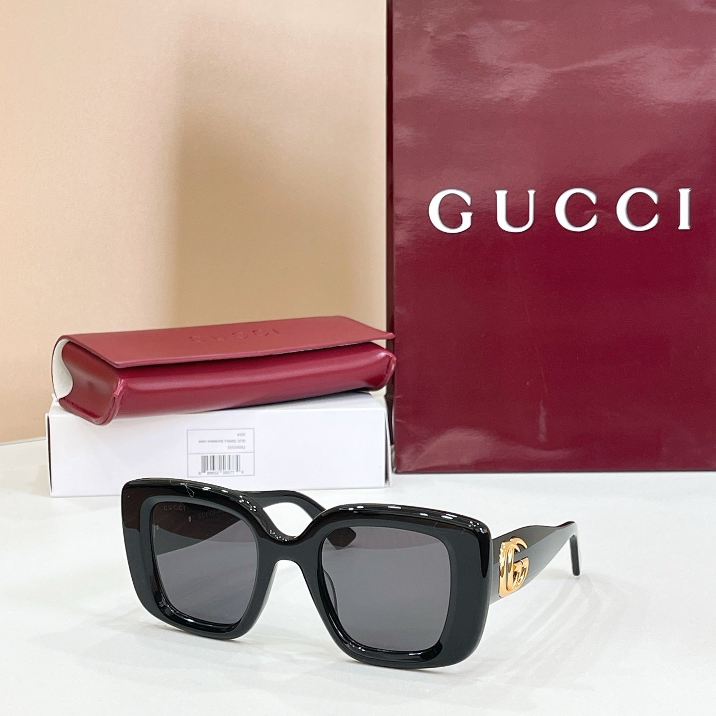 Gucci sunglasses with black frames and tinted lenses, gold GG logo on temple.