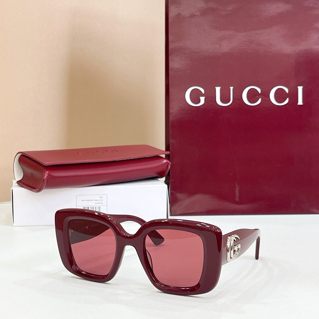 Gucci sunglasses with burgundy frames and pink-tinted lenses, gold GG logo temple.