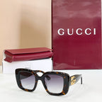 Gucci sunglasses with dark frames and tinted lenses, gold GG logo on temple.