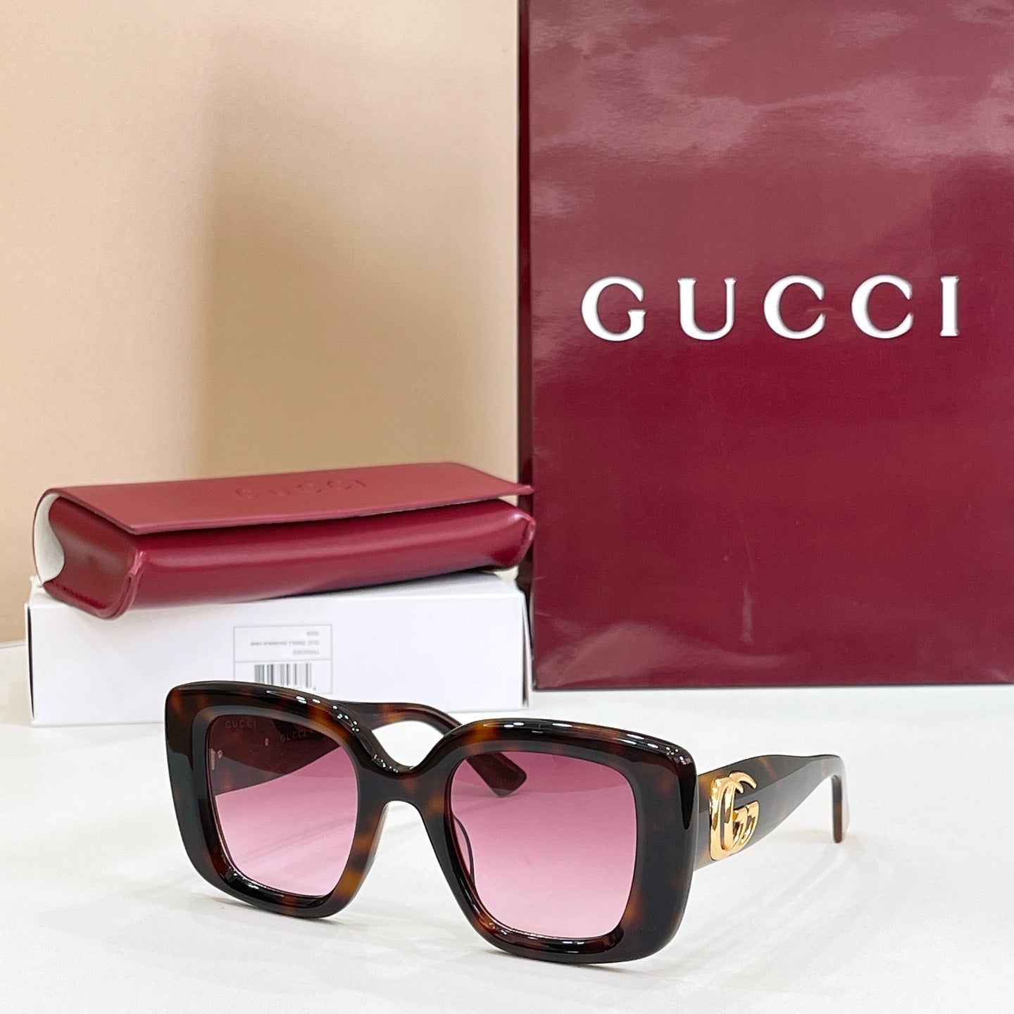 Gucci sunglasses with tortoiseshell frames and pink-tinted lenses, gold GG logo temple.