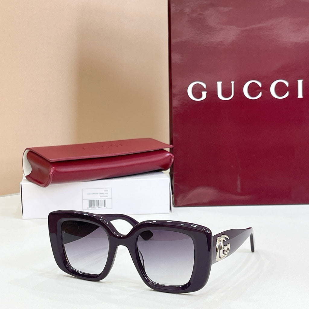 Gucci sunglasses with dark purple frames and tinted lenses, gold GG logo temple detail.