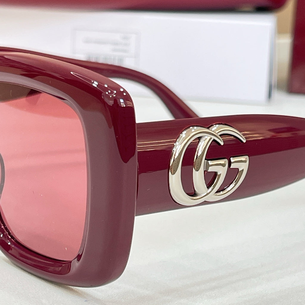 Burgundy sunglasses with tinted lenses and gold-tone interlocking GG logo temple