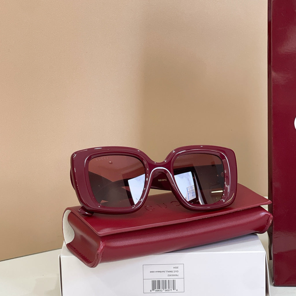 Burgundy square sunglasses with tinted lenses, displayed on box and case