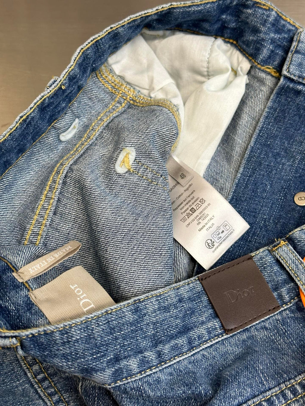 Dior pants, open waistband showing care tags inside light blue denim pockets
