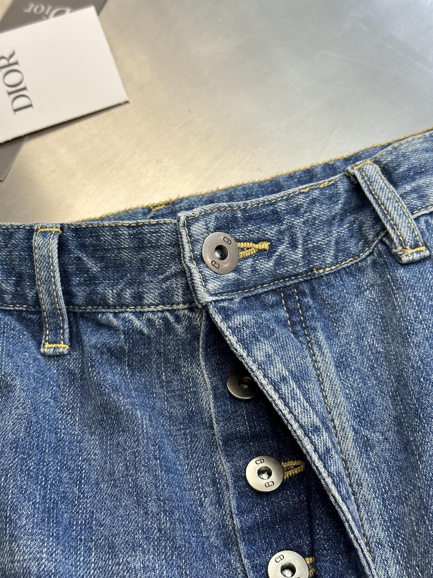 Dior pants, denim waistband close-up with button fly and brand hardware