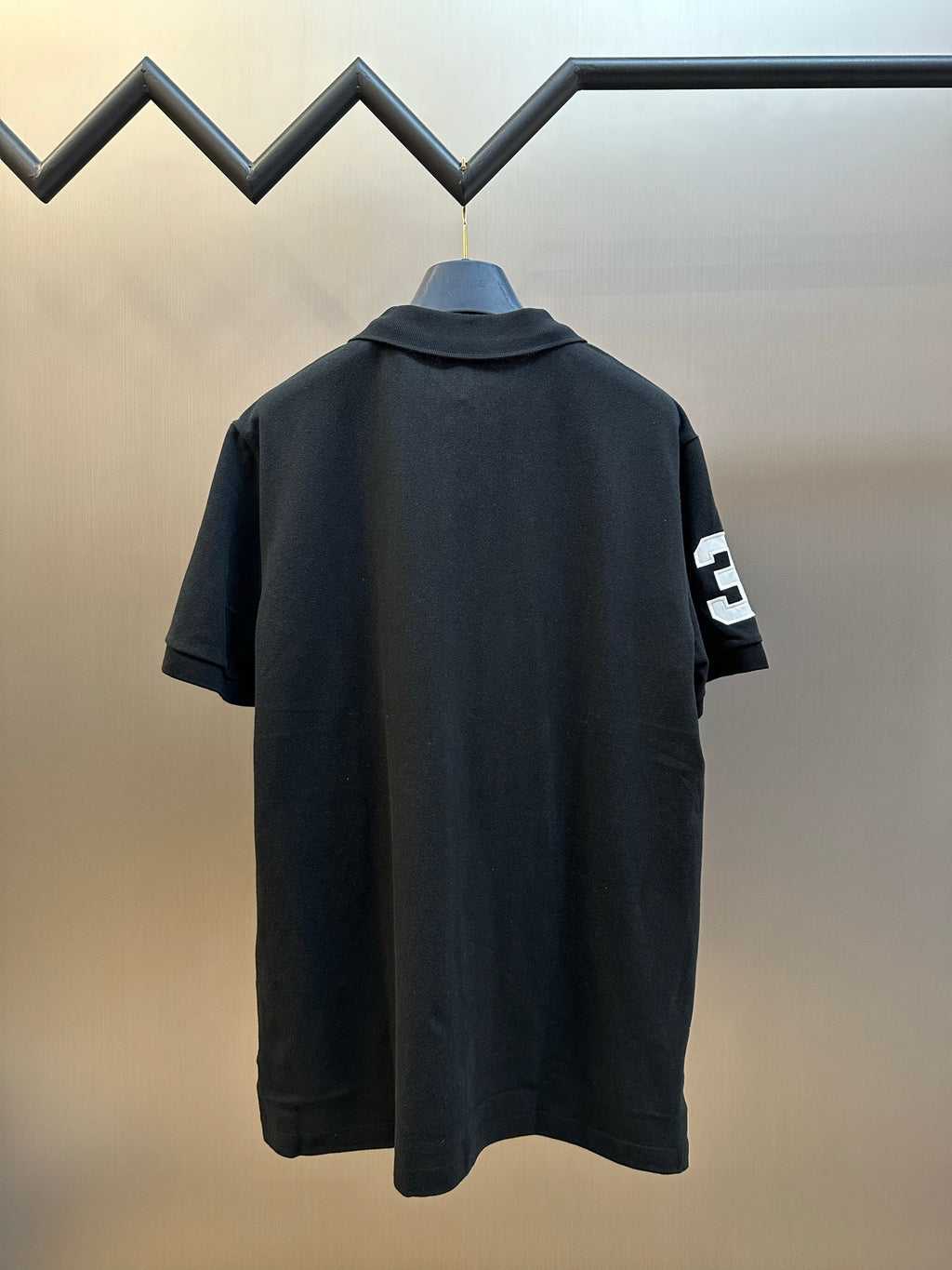 Dark navy polo shirt back with small white number 3 patch