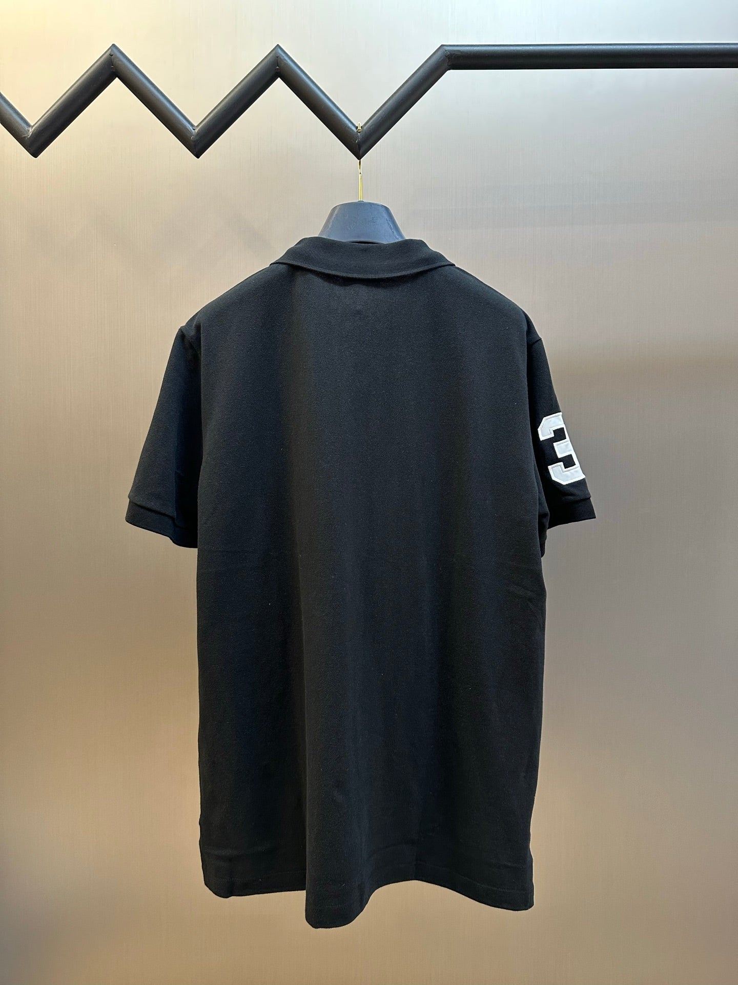 Dark navy polo shirt back with small white number 3 patch