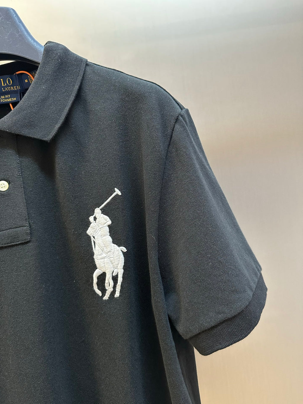 Dark navy polo shirt sleeve with white rider logo