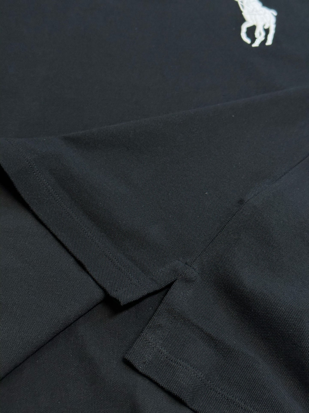 Dark navy polo shirt fabric with crossed seam detail at hem