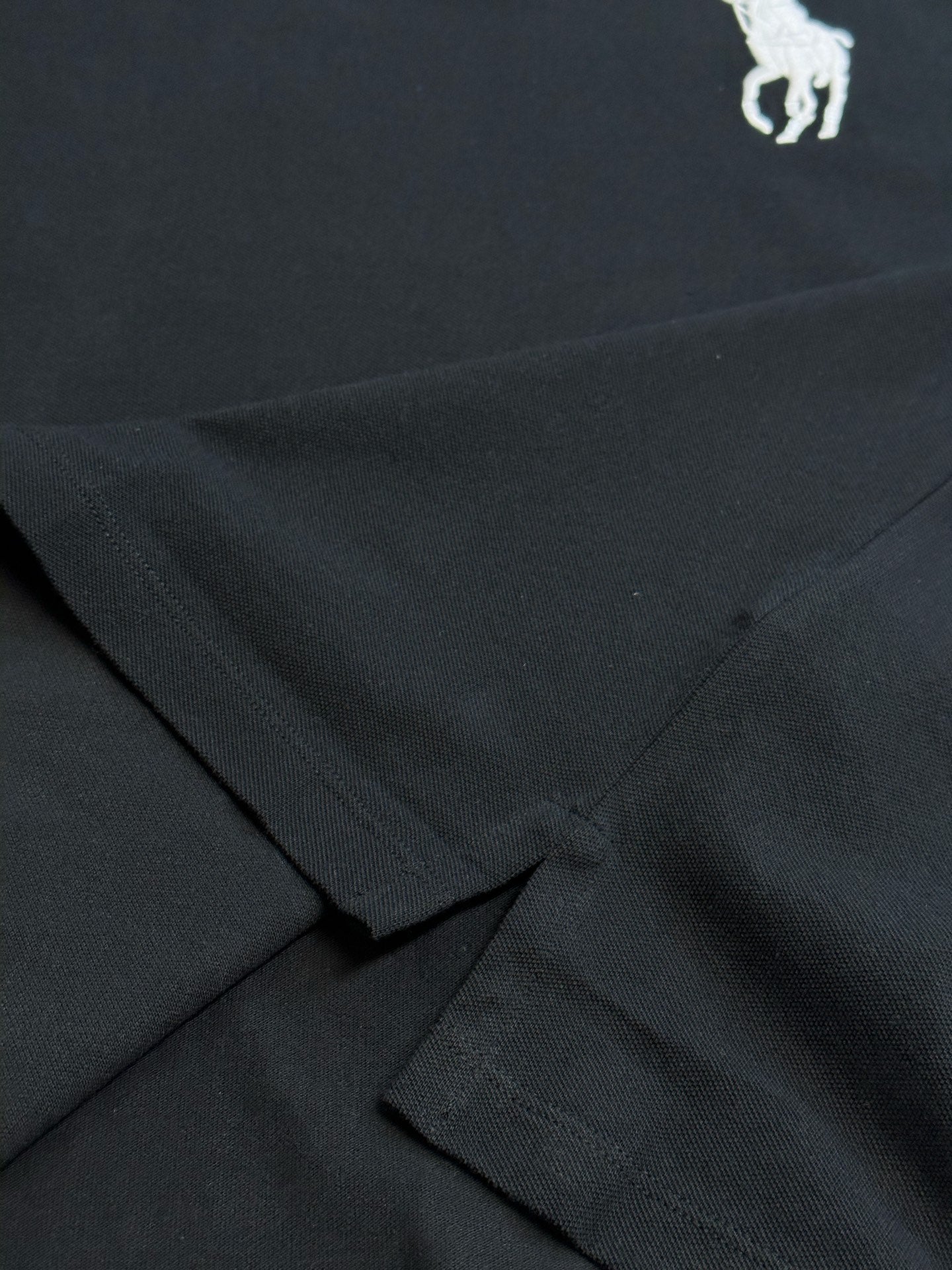 Dark navy polo shirt fabric with crossed seam detail at hem