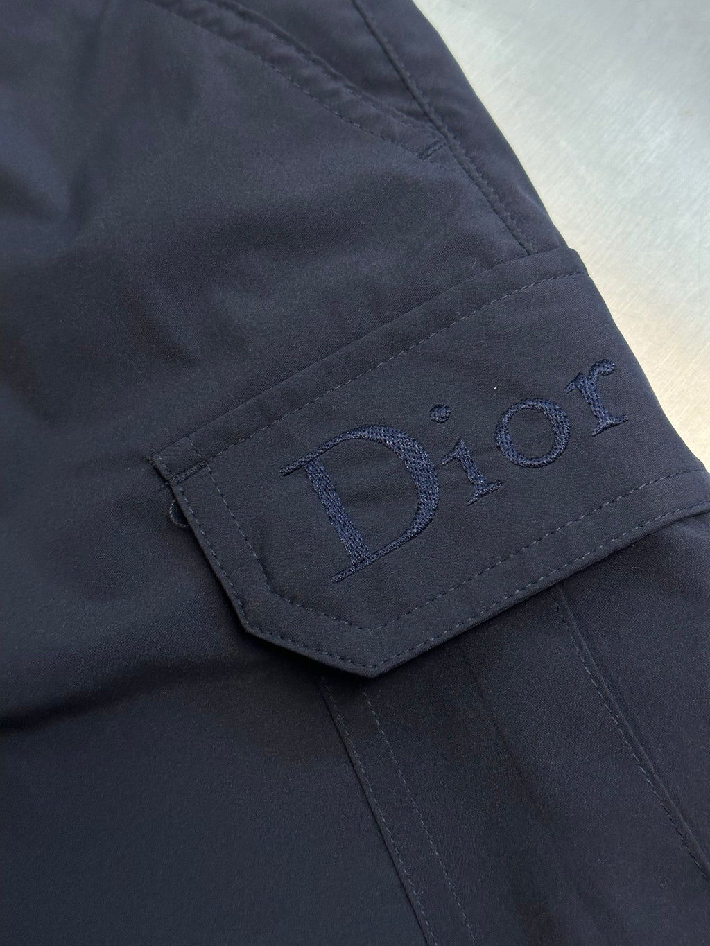 Navy cargo shorts close-up of embroidered Dior logo on cargo pocket