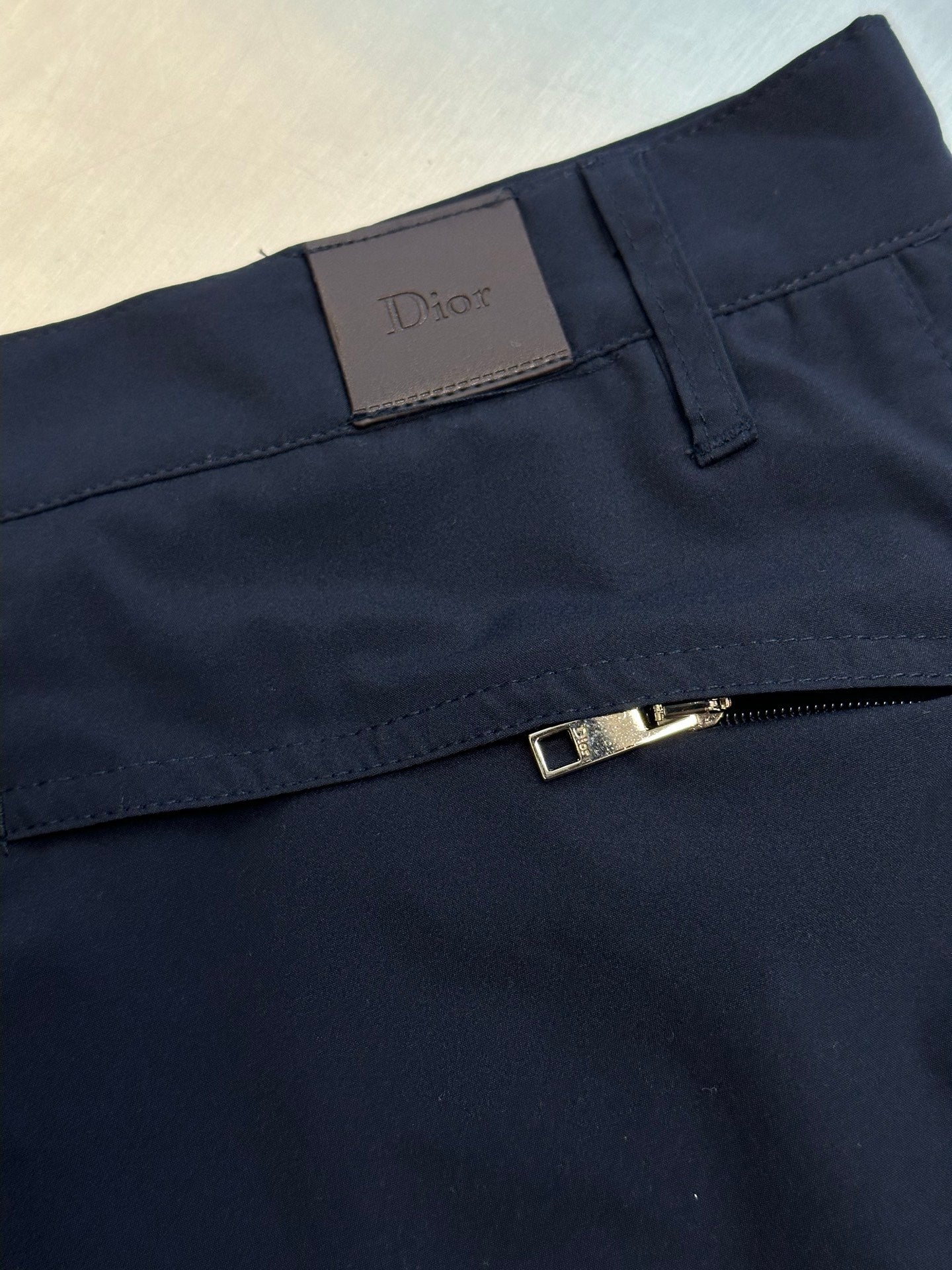 Navy cargo shorts with brand patch and metal belt detail at waistband
