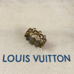 Gold stud earring with decorative motif on beige fabric with Louis Vuitton logo