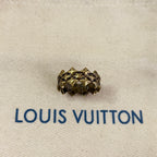 Gold stud earring on beige fabric with Louis Vuitton logo